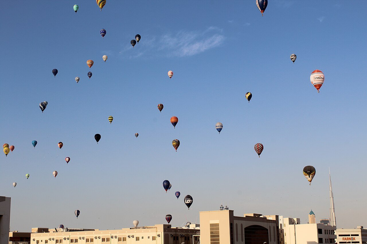 Heteluchtballon stijgt bij zonsopgang op boven de duinen bij Dubai