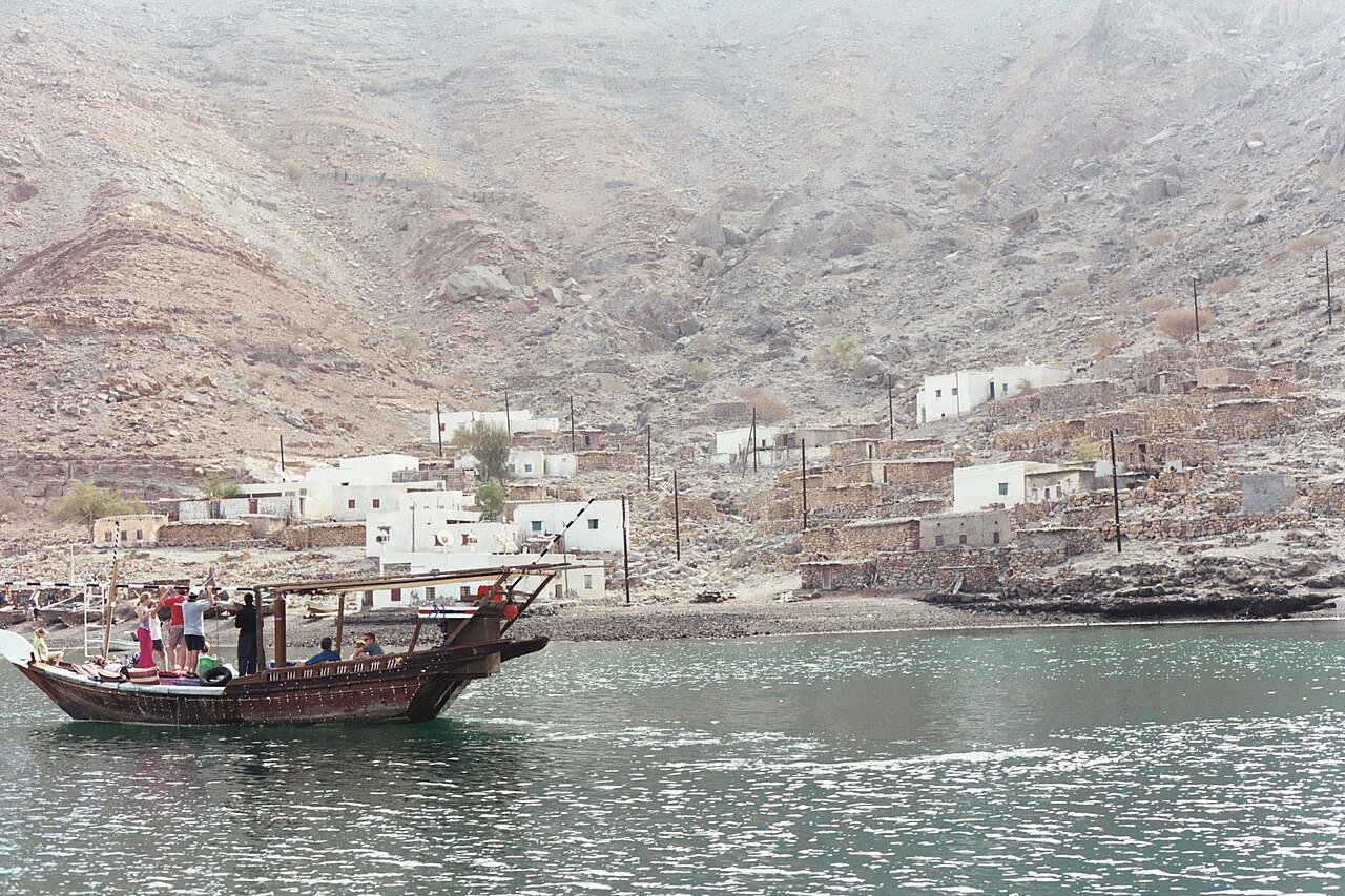 Steile rotswanden dalen af naar het blauwe water van de Musandam-fjorden