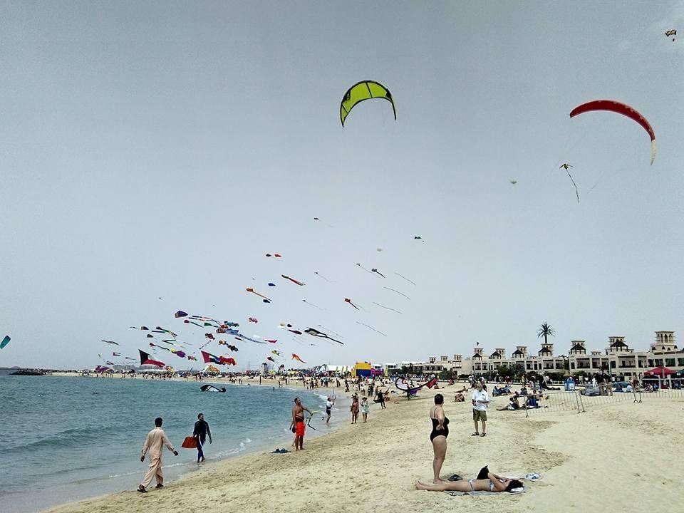 Openbaar strand van Kite Beach in Dubai met zwemmers en surfers