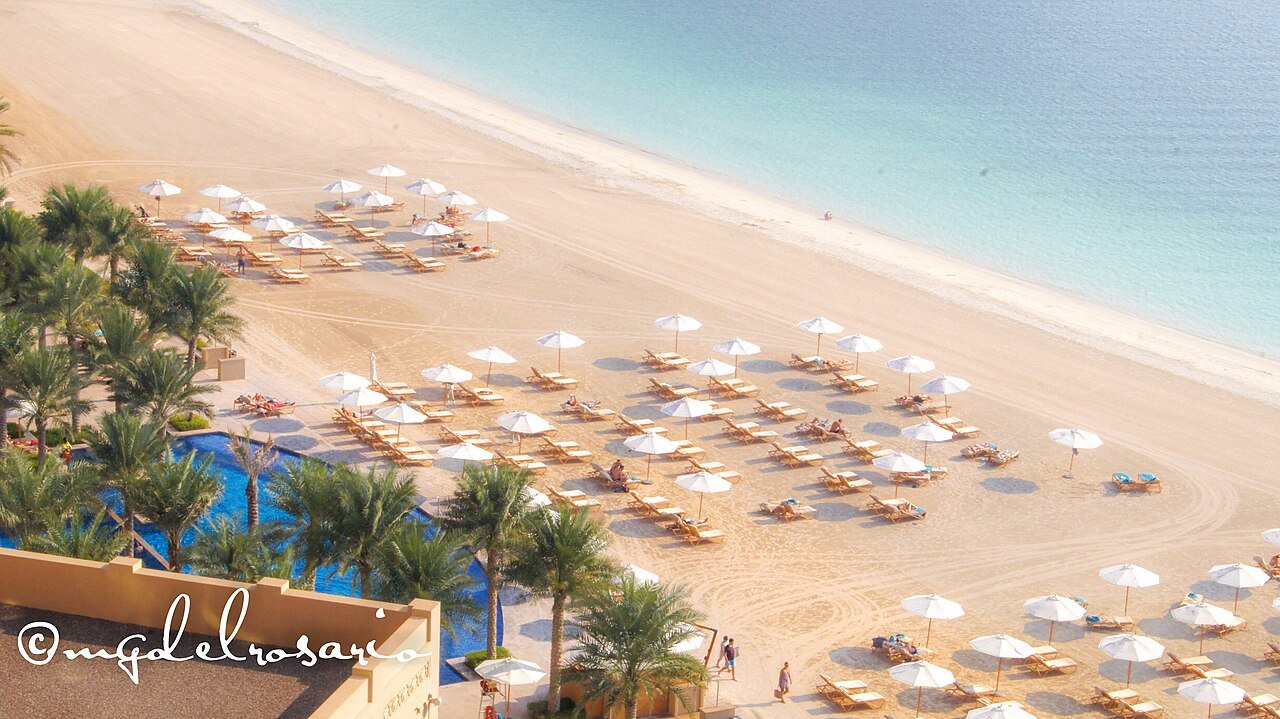Ligbedden en parasols bij het zwembad van een resort aan zee in Dubai